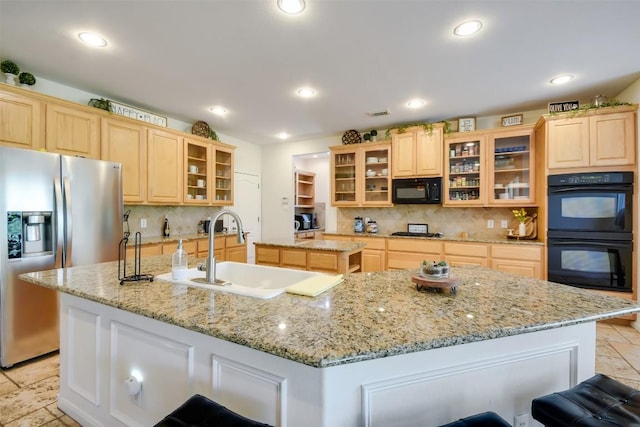 kitchen with black appliances, a center island with sink, a sink, light brown cabinetry, and decorative backsplash