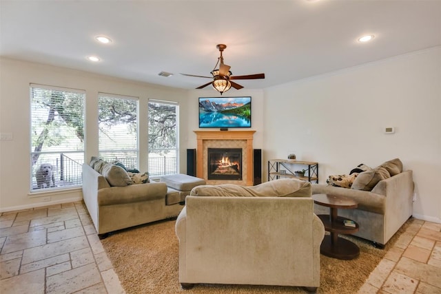 living area with stone tile floors, a glass covered fireplace, recessed lighting, baseboards, and a ceiling fan