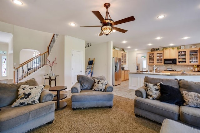 living area featuring stairway, healthy amount of natural light, recessed lighting, ceiling fan, and arched walkways
