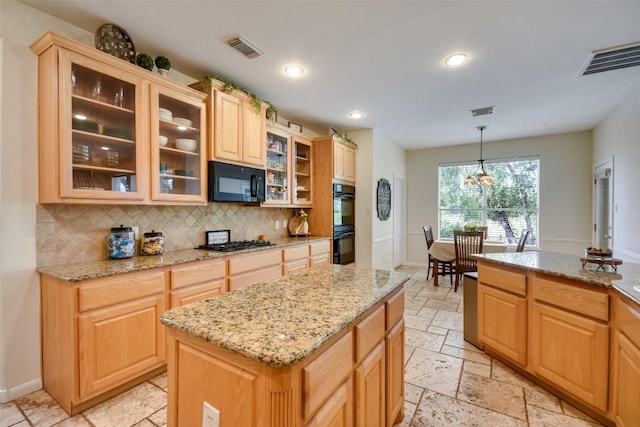 kitchen with black appliances, decorative backsplash, stone tile floors, light stone counters, and hanging light fixtures