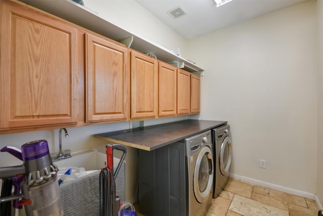 washroom with cabinet space, separate washer and dryer, stone tile flooring, and baseboards