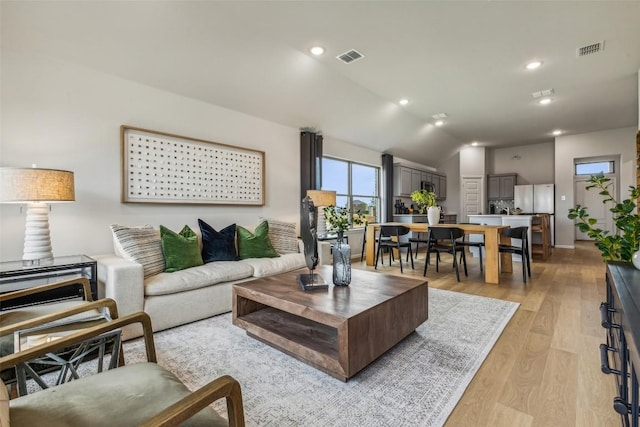 208 Hidalgo Ln, Elgin, TX 78621 - living room featuring light wood finished floors, vaulted ceiling, and recessed lighting