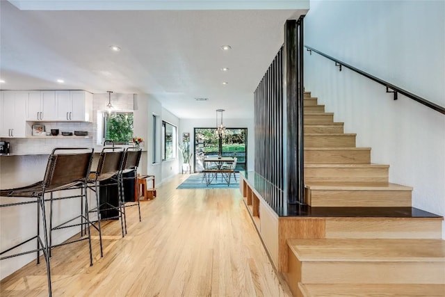 staircase with wood finished floors, recessed lighting, and a chandelier