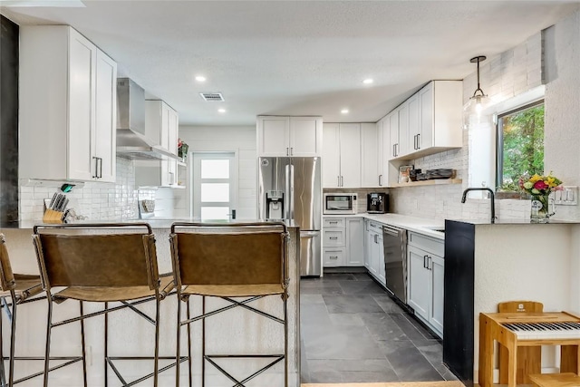 kitchen featuring appliances with stainless steel finishes, wall chimney range hood, a sink, plenty of natural light, and recessed lighting