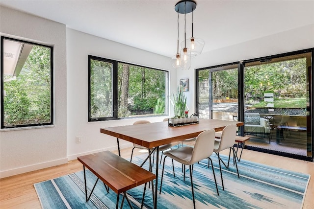 dining room with baseboards, light wood-style flooring, and a textured wall