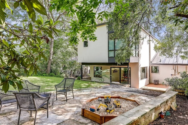 back of property featuring stucco siding, a patio, a fire pit, and a yard