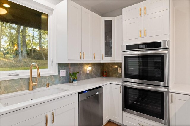 146 Caldwell Ranch Rd, Cedar Creek, TX 78612 - kitchen featuring appliances with stainless steel finishes, a sink, white cabinets, glass insert cabinets, and light countertops