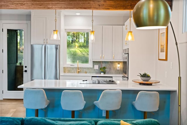 146 Caldwell Ranch Rd, Cedar Creek, TX 78612 - kitchen with appliances with stainless steel finishes, white cabinetry, a kitchen breakfast bar, tasteful backsplash, and hanging light fixtures