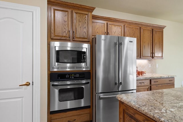 103 Nueces Trl, Georgetown, TX 78633 - kitchen featuring stainless steel appliances, brown cabinets, decorative backsplash, and light stone counters