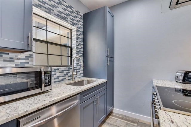 1908 San Antonio St Unit 213, Austin, TX 78705 - kitchen with appliances with stainless steel finishes, a sink, light wood-style floors, baseboards, and backsplash