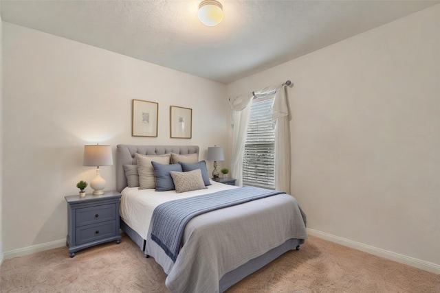 bedroom with light colored carpet and baseboards