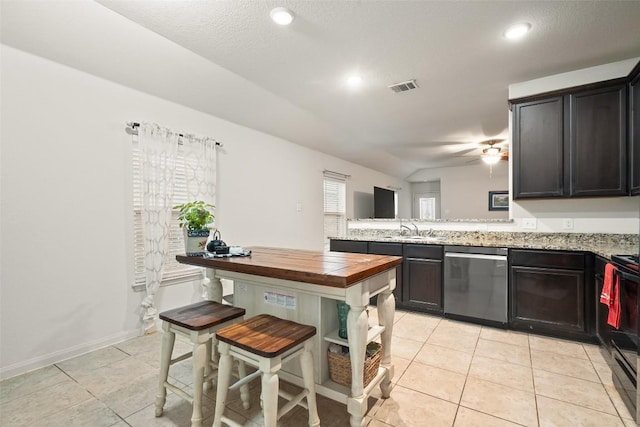 kitchen with dishwasher, a sink, light tile patterned floors, vaulted ceiling, and a peninsula