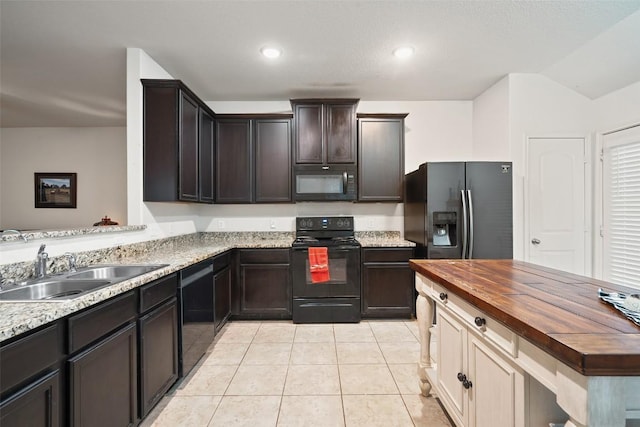 kitchen with black appliances, a sink, wooden counters, light tile patterned floors, and dark brown cabinetry