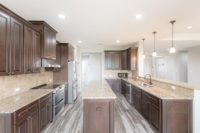 121 Grassy Ln, Elgin, TX 78621 - kitchen with stainless steel appliances, a peninsula, a center island, light wood-type flooring, and under cabinet range hood