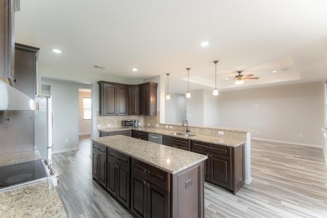 121 Grassy Ln, Elgin, TX 78621 - kitchen featuring a ceiling fan, stainless steel appliances, light wood-style floors, a center island, and decorative backsplash