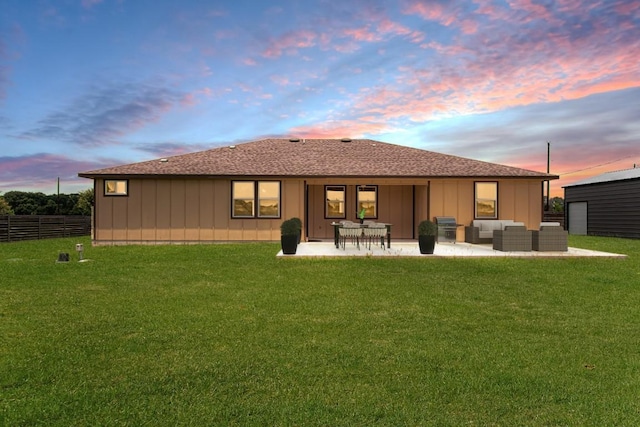 121 Grassy Ln, Elgin, TX 78621 - back of house at dusk with outdoor lounge area, a patio, board and batten siding, and a shingled roof