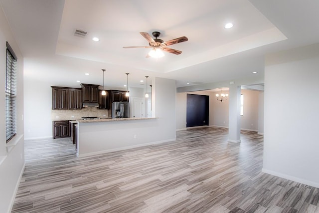 121 Grassy Ln, Elgin, TX 78621 - unfurnished living room with a tray ceiling, light wood-style flooring, a chandelier, a ceiling fan, and recessed lighting