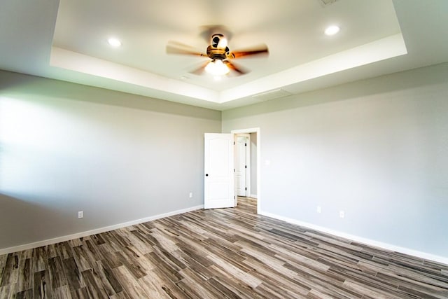 121 Grassy Ln, Elgin, TX 78621 - empty room featuring a tray ceiling, wood finished floors, ceiling fan, and recessed lighting