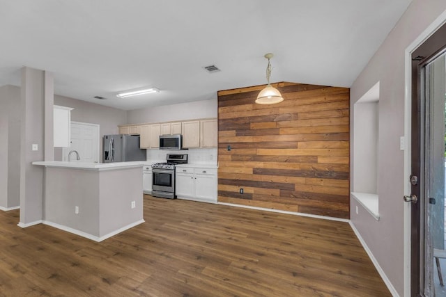 906 Mammoth Ct, Round Rock, TX 78681 - kitchen with appliances with stainless steel finishes, dark wood-style flooring, a peninsula, light countertops, and wood walls