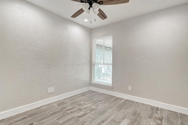 spare room featuring wood tiled floors, a textured wall, baseboards, ceiling fan, and healthy amount of natural light