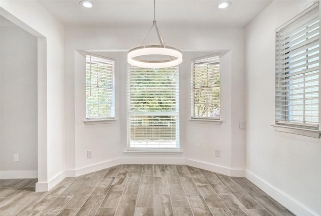 unfurnished dining area featuring wood finished floors, recessed lighting, healthy amount of natural light, and baseboards