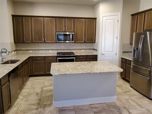 539 Tanda Ln, Hutto, TX 78634 - kitchen featuring appliances with stainless steel finishes, a sink, light stone countertops, and backsplash