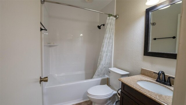 full bathroom featuring toilet, shower / bath combination with curtain, vanity, and a textured wall