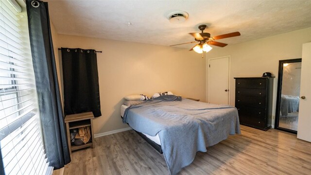 bedroom featuring wood finished floors, baseboards, and a ceiling fan