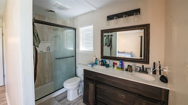 full bathroom with a stall shower, double vanity, wood finished floors, and toilet