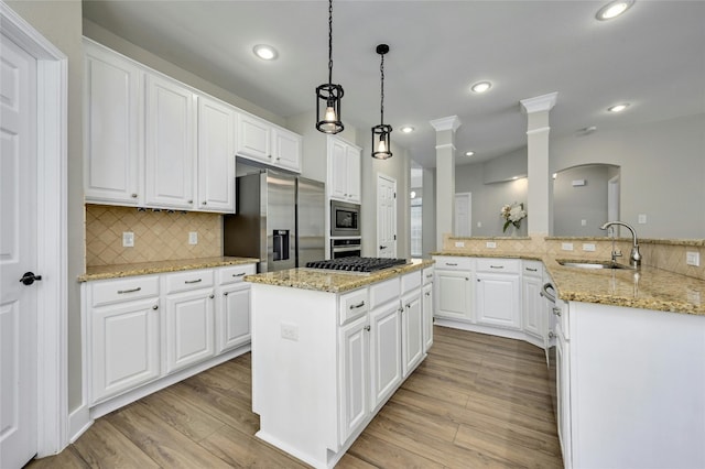 4933 China Garden Dr, Austin, TX 78730 - kitchen with a sink, stainless steel appliances, a kitchen island, light wood-type flooring, and tasteful backsplash