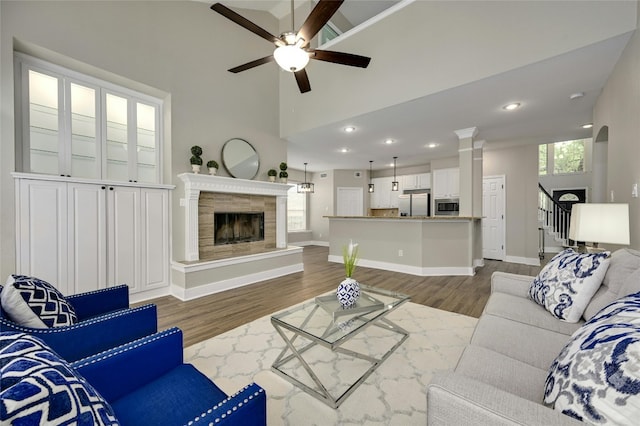 4933 China Garden Dr, Austin, TX 78730 - living room featuring a ceiling fan, wood finished floors, a tiled fireplace, high vaulted ceiling, and baseboards