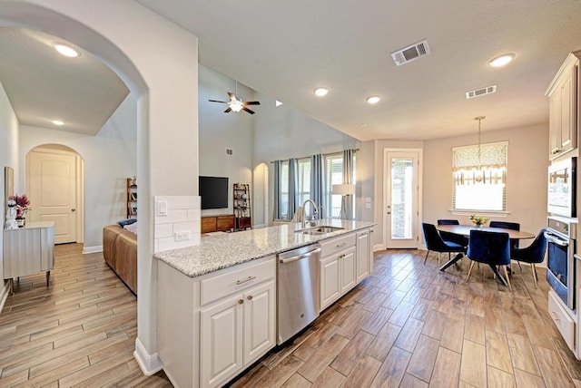 1816 Ficuzza Way, Leander, TX 78641 - kitchen featuring stainless steel appliances, arched walkways, light wood-style flooring, a ceiling fan, and hanging light fixtures