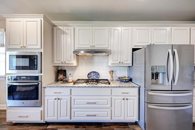 1816 Ficuzza Way, Leander, TX 78641 - kitchen featuring appliances with stainless steel finishes, dark wood finished floors, under cabinet range hood, and light stone counters
