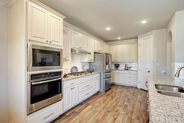 1816 Ficuzza Way, Leander, TX 78641 - kitchen featuring stainless steel appliances, under cabinet range hood, decorative backsplash, light wood-type flooring, and recessed lighting