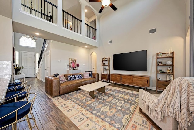 1816 Ficuzza Way, Leander, TX 78641 - living room featuring arched walkways, a towering ceiling, a ceiling fan, wood finished floors, and stairs
