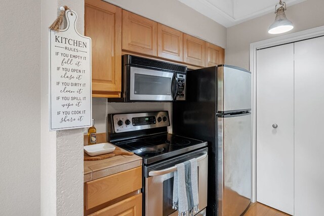 kitchen with stainless steel appliances, light brown cabinets, and tile counters