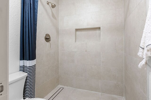 full bath with tiled shower and toilet