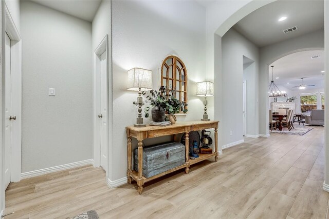hall featuring arched walkways, wood finished floors, baseboards, and recessed lighting
