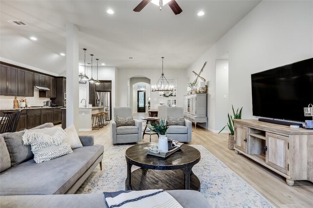 living room featuring ceiling fan, arched walkways, light wood-type flooring, recessed lighting, and a chandelier