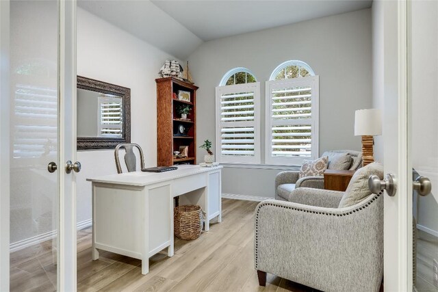 home office with light wood-type flooring, baseboards, and lofted ceiling