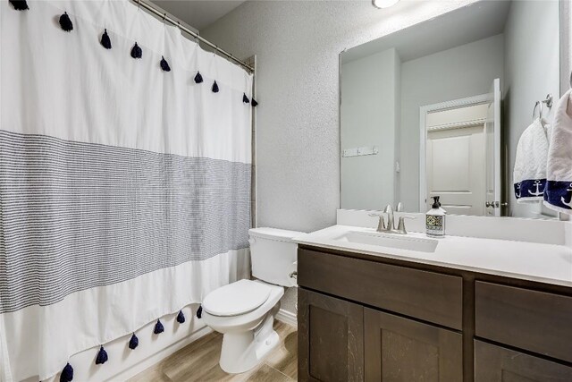 bathroom with a textured wall, toilet, and vanity