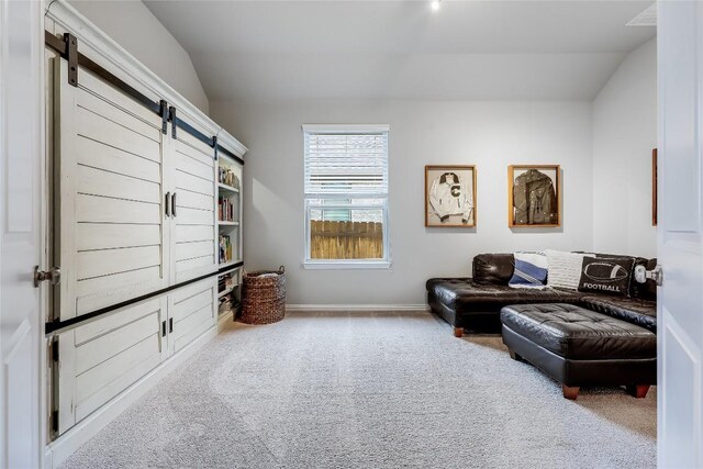 living area with a barn door, carpet, and baseboards
