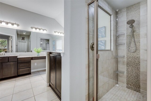 full bath featuring a tile shower, tile patterned flooring, vaulted ceiling, and vanity