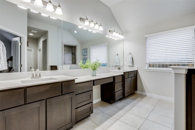 bathroom featuring lofted ceiling, tile patterned floors, double vanity, and baseboards