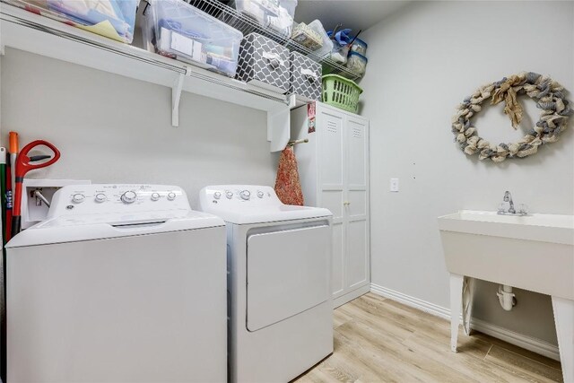 washroom with washer and dryer, light wood-style floors, and baseboards