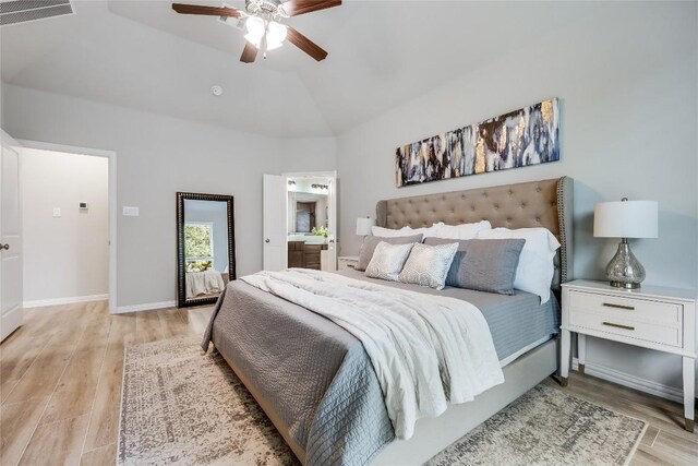 bedroom with light wood finished floors, ceiling fan, ensuite bathroom, high vaulted ceiling, and baseboards