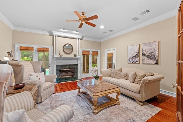 living room with wood finished floors, ceiling fan, a high end fireplace, crown molding, and recessed lighting