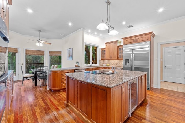 8900 Bell Mountain Dr, Austin, TX 78730 - kitchen featuring brown cabinetry, stainless steel appliances, beverage cooler, plenty of natural light, and ornamental molding