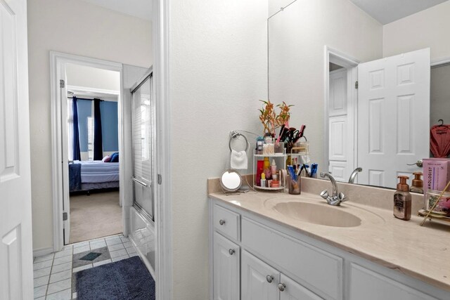bathroom with a shower with shower door, tile patterned flooring, vanity, and ensuite bath