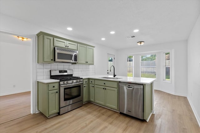 2310 Raintree Path, Round Rock, TX 78664 - kitchen featuring green cabinetry, appliances with stainless steel finishes, a peninsula, light countertops, and backsplash